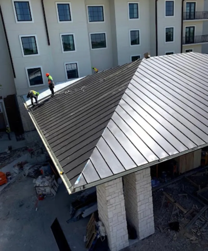 Crew installing standing seam metal roof panels on a commercial project in Dalton
